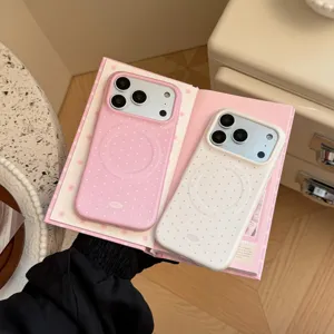 Détail de coques de téléphone magnétiques à pois roses et blancs sur un livre.