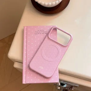 Gros plan d'une coque MagSafe à pois roses posée sur un carnet assorti de style ins