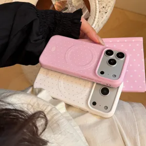 Gros plan de coques iPhone magnétiques à pois roses et blancs tenues
