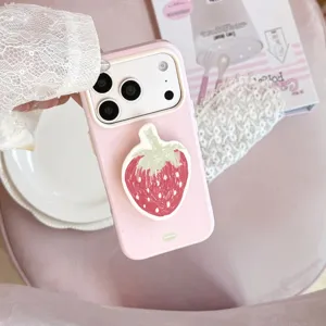 Détail d'une coque iPhone rose avec un support de téléphone en forme de fraise