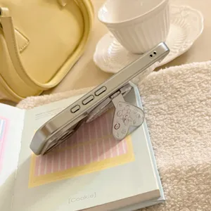 Détail du support de téléphone pliable en forme de cœur avec ourson sur coque argentée.