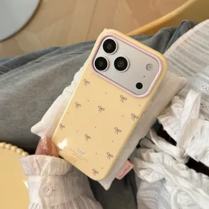 Custodia iPhone giallo crema con accenti rosa e delicati motivi a nastro da vicino.