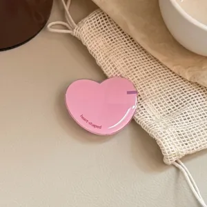 Close-up detail van een roze hartvormige uitschuifbare telefoonhouder op een beige basis