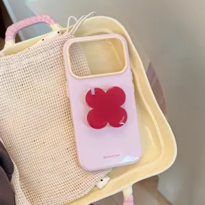 Gros plan du support de téléphone en forme de trèfle rouge sur une coque rose.