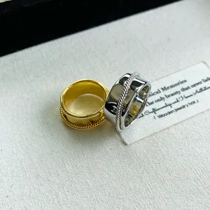 Detailansicht von gold- und silberfarbenen breiten Ringen mit zentralem Seilmuster-Design
