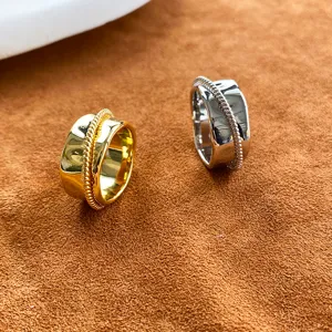 Nahaufnahme von gold- und silbernen Ringen mit Seildetail auf braunem Wildleder.