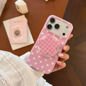 Gros plan d'une coque iPhone à pois roses avec un support de téléphone en forme d'étoile.