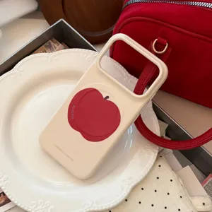 Gros plan d'une coque iPhone crème avec un motif de pomme rouge et un texte minimaliste chic.