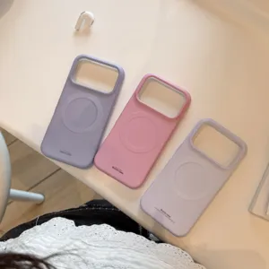 Trois coques magnétiques mates pour téléphone en violet et rose pastel sur bureau blanc