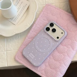 Détail macro d'une coque iPhone magnétique violette à pois sur un tapis rose à carreaux