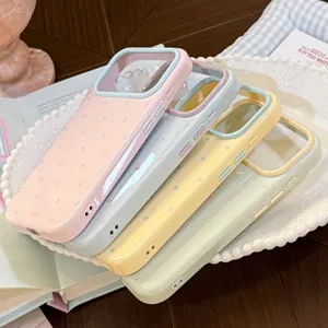 Quatre coques iPhone aux couleurs macaron avec des pois blancs sur un plateau décoratif