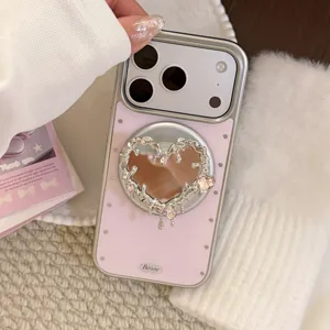 Vue détaillée d'une coque iPhone rose avec support miroir en cœur argenté et clous