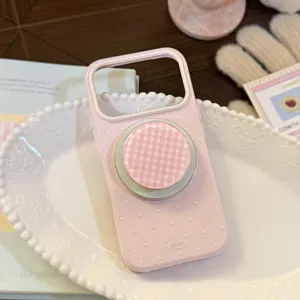 Détail de coque iPhone rose à pois avec finition pailletée et support magnétique.