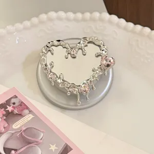 Gros plan d'un support de téléphone miroir en forme de cœur argenté et rose strass