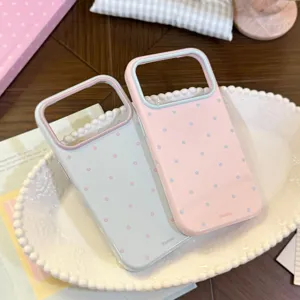 Gros plan de coques iPhone à pois macaron avec bordures contrastées sur plateau