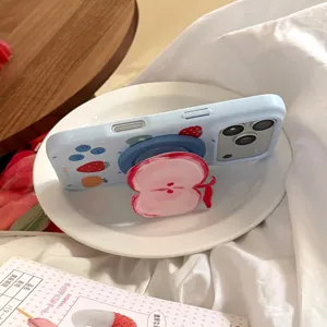 Detail of light blue iPhone case featuring a 3D red apple pop socket and fruit graffiti