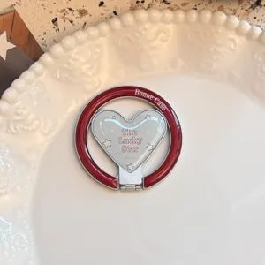 Detail of vintage red heart-shaped magnetic phone ring stand on a decorative plate