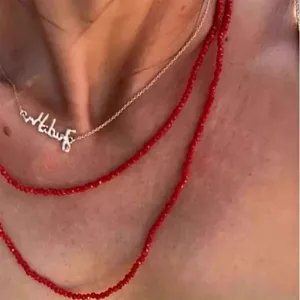 Dettaglio ravvicinato di collane di spinello rosso a strati con ciondolo a nome Albus.