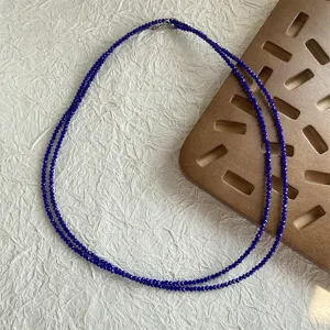 Primo piano di una collana a due fili di perline sfaccettate blu scuro per layering