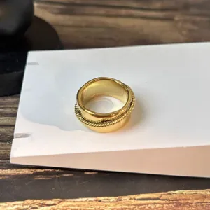 Detailansicht eines breiten Goldrings mit einem gedrehten Seiltextur-Design.