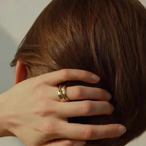 Nahaufnahme eines klobigen, goldfarbenen Designerrings mit Hammerschlag-Textur.