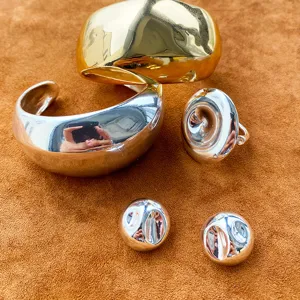 Nahaufnahme eines minimalistischen Schmucksets in Gold und Silber auf braunem Velours