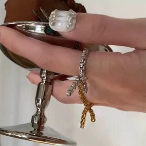 Detailansicht minimalistischer Kettengliedringe in Gold und Silber an der Hand des Models