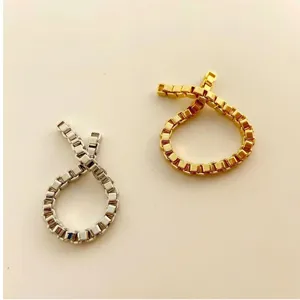 Detailansicht von eleganten Box-Link-Kettenringen in Gold und Silber auf beigem Grund