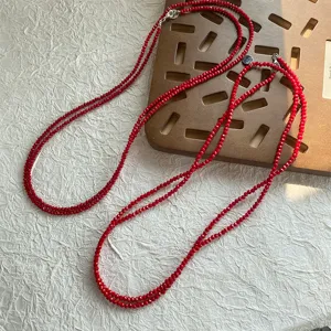 Dettaglio macro delle perline di spinello rosso sfaccettate su una collana a strati