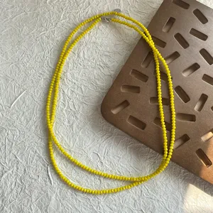 Dettaglio macro di piccole perle di spinello giallo sfaccettate su una collana