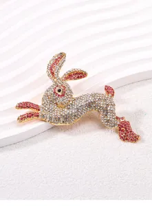 Detail view of a golden running rabbit brooch with pink and white crystal rhinestones.