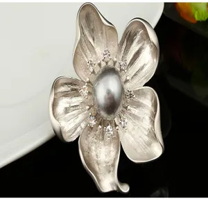 Detailed close-up showing the brushed silver finish and central pearl of the flower brooch