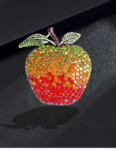 Detailed macro view of an apple brooch encrusted with vibrant colorful rhinestones.