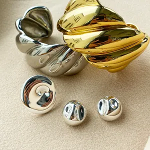 Nahaufnahme von minimalistischen goldenen und silbernen Ringen und Ohrringen mit Textur