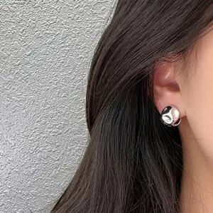 Nahaufnahme minimalistischer silberner Ohrstecker mit hochglänzendem Wirbelmuster.