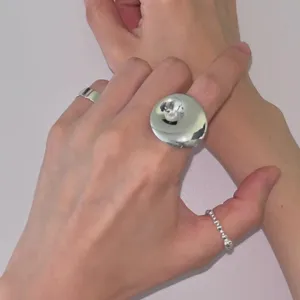Detailansicht eines minimalistischen glänzenden Hurrikan-Rings und Perlenbands.
