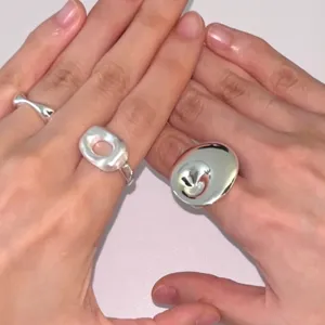 Nahaufnahme minimalistischer glänzender Silberringe an Händen mit Strukturfinish