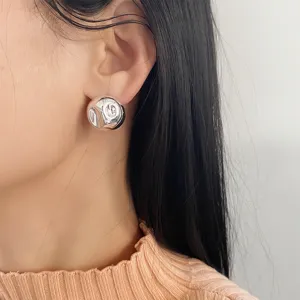 Nahaufnahme eines minimalistischen silbernen Ohrrings mit strukturierter Kugelform am Ohr