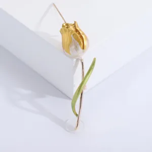 Detailed close-up of an elegant gold and pearl-white tulip brooch pin with green leaf