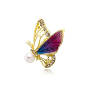Detailweergave van emaille vlinderbroche met paarse gradiënt vleugels en parelaccent