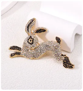 Detailed close-up of a golden alloy rabbit brooch encrusted with white and black rhinestones
