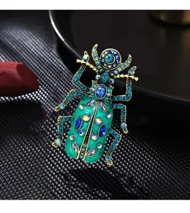 Detail van een vintage keverbrosche met groen emaille en glinsterende blauwe steentjes