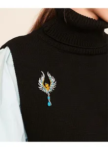 Vista detallada del elegante broche de ala de ángel con cristaux azules en suéter negro