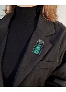 Detailweergave van vintage keverspeld met groene strass-steentjes op blazerrevers.