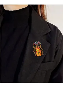 Vintage strass kever broche op het revers van een zwarte blazer