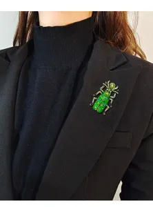 Detailopname van een vintage groene strass kever speld op de revers van een blazer.