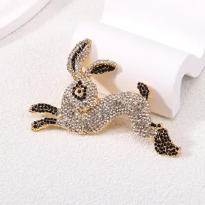 Sparkling running rabbit brooch pin with clear and black rhinestones in gold tone finish.