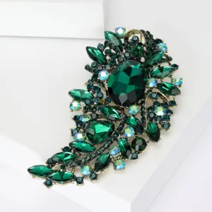Detalle de broche vintage con cristales verde esmeralda y pedrería irisada en fondo blanco.