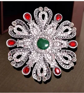 Vue détaillée d'une broche baroque vintage avec cristaux verts et rouges.