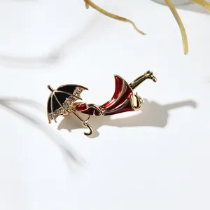 Dettaglio macro dell'elegante spilla a ombrello in smalto rosso e nero con strass brillanti